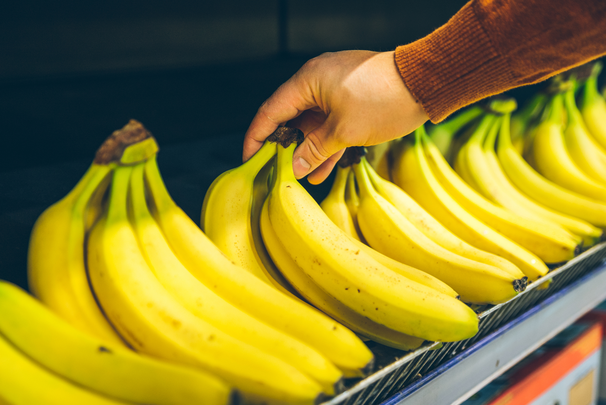 mans hand take bananas from shelf of store. healthy food. shopping concept