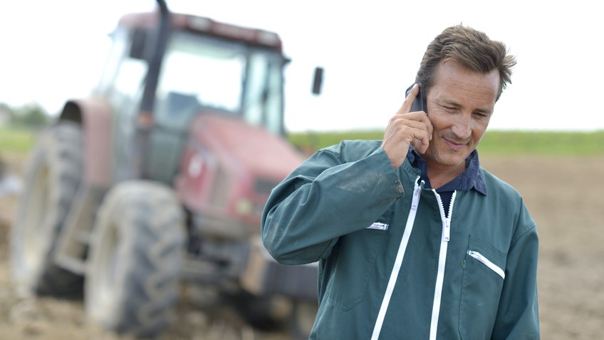 Farmer walking in field and talking on mobile phone