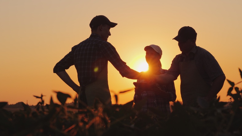 A group of farmers in the field, shaking hands. Family Agribusiness