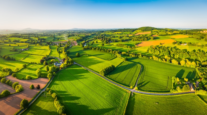 Aerial panorama over idyllic green summer farm fields crops pasture