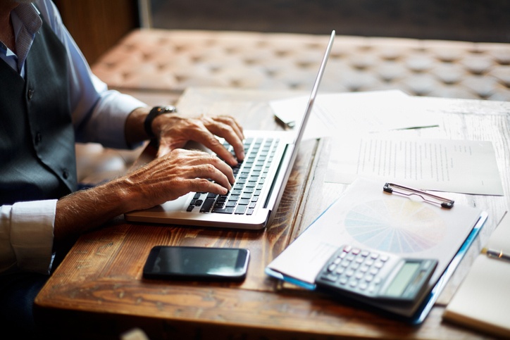 Senior businessman typing on a laptop in a coworking space