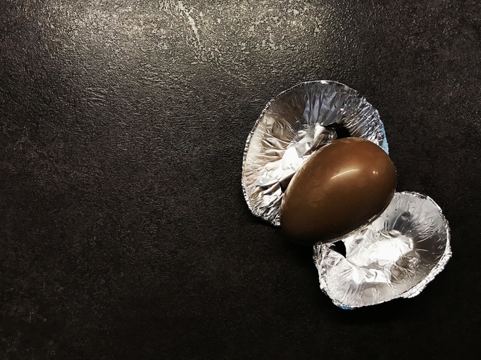 Easter chocolate kinder egg with a foil on a black table